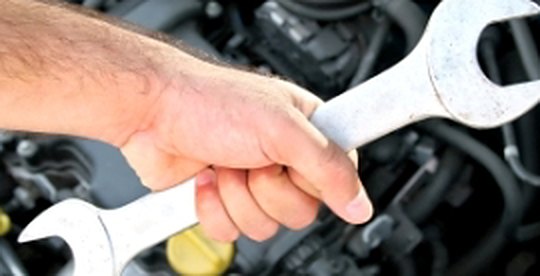 Mechanic with a spanner over an engine